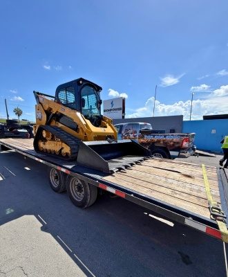 CAT compact track loader on a trailer during an IronPower Industries customer delivery