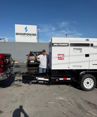 Customer beside an MQ Power diesel generator on a trailer at IronPower Industries