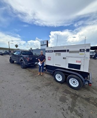 Customer standing beside an MQ Power diesel generator on a trailer at IronPower Industries