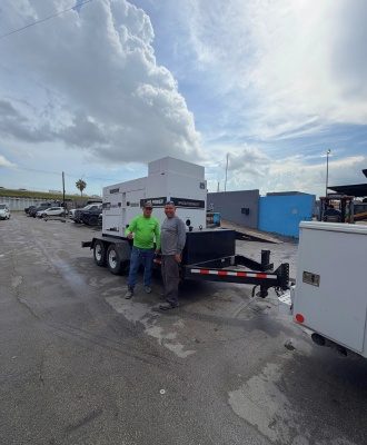 Two customers beside an MQ Power diesel generator on a trailer at IronPower Industries
