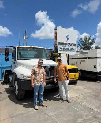 Two customers standing beside an International day cab truck tractor at IronPower Industries